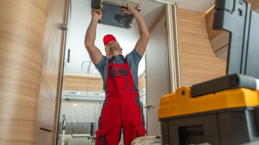 Close-up of RV air conditioner with technician using diagnostic tools on rooftop unit