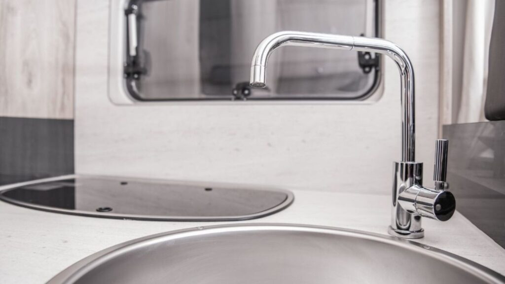 Inside view of an RV plumbing system with water lines and fittings